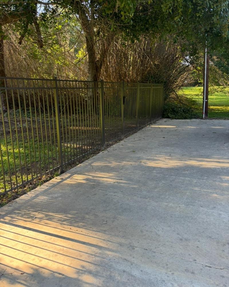 Black metal fence along a concrete driveway